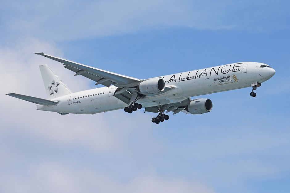 Low-angle view of a Singapore Airlines plane flying against a blue sky.